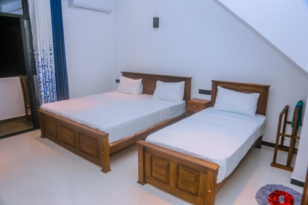 two twin beds in a room withthritisthritislictslicts at Mirissa Breeze in Mirissa