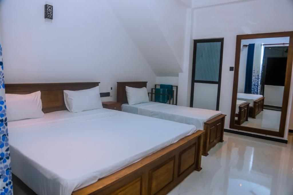 two beds in a room with a mirror at Mirissa Breeze in Mirissa