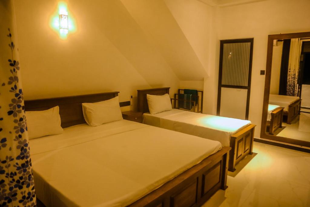 two beds in a small room with a window at Mirissa Breeze in Mirissa