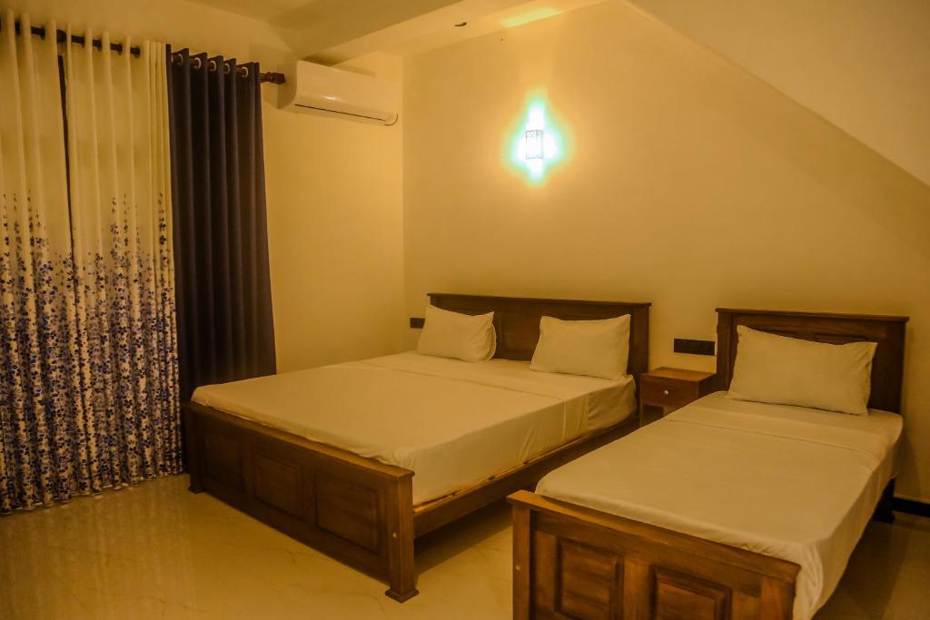 a bedroom with two beds and a window at Mirissa Breeze in Mirissa