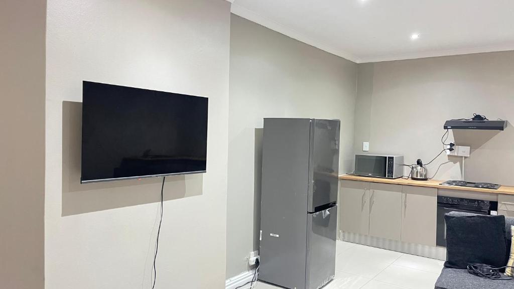 a kitchen with a tv on a wall at Holiday Accommodation in Gqeberha