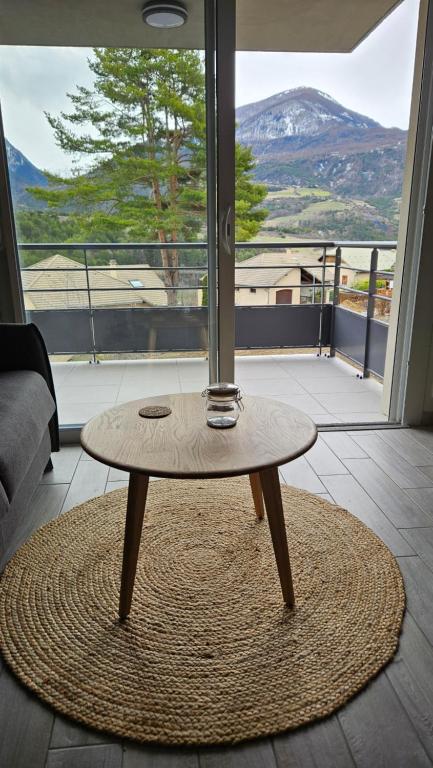 - une table basse dans une chambre dotée d'une grande fenêtre dans l'établissement Confort face montagne, à Embrun