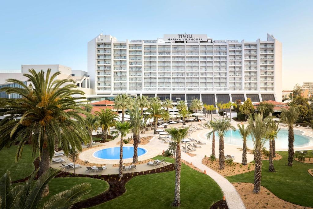 a hotel with palm trees and a large building at Tivoli Marina Vilamoura in Vilamoura