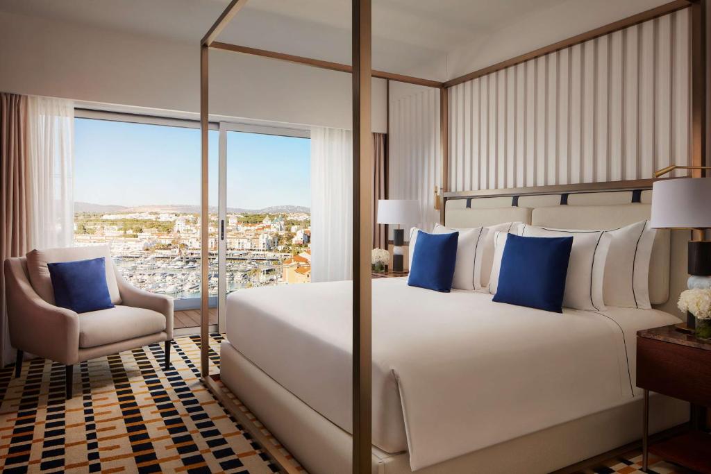 a bedroom with a bed and a chair and a window at Tivoli Marina Vilamoura in Vilamoura