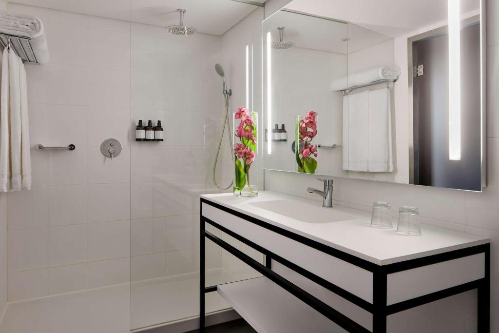 a white bathroom with a sink and a shower at Tivoli Marina Vilamoura in Vilamoura