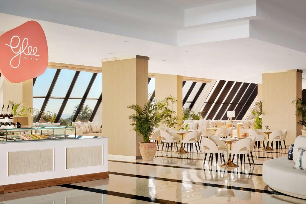 a restaurant with white chairs and tables and windows at Tivoli Marina Vilamoura in Vilamoura
