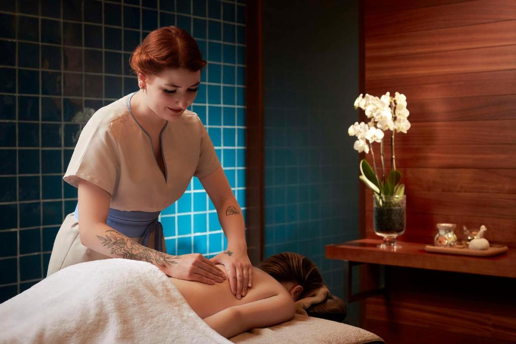 a woman getting a massage from a woman sitting on a bed at Tivoli Marina Vilamoura in Vilamoura