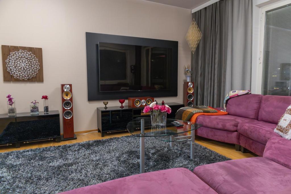 Una sala de estar con un sofá morado y un televisor. en Luxury apartment with sauna, grill and garage, en Tampere