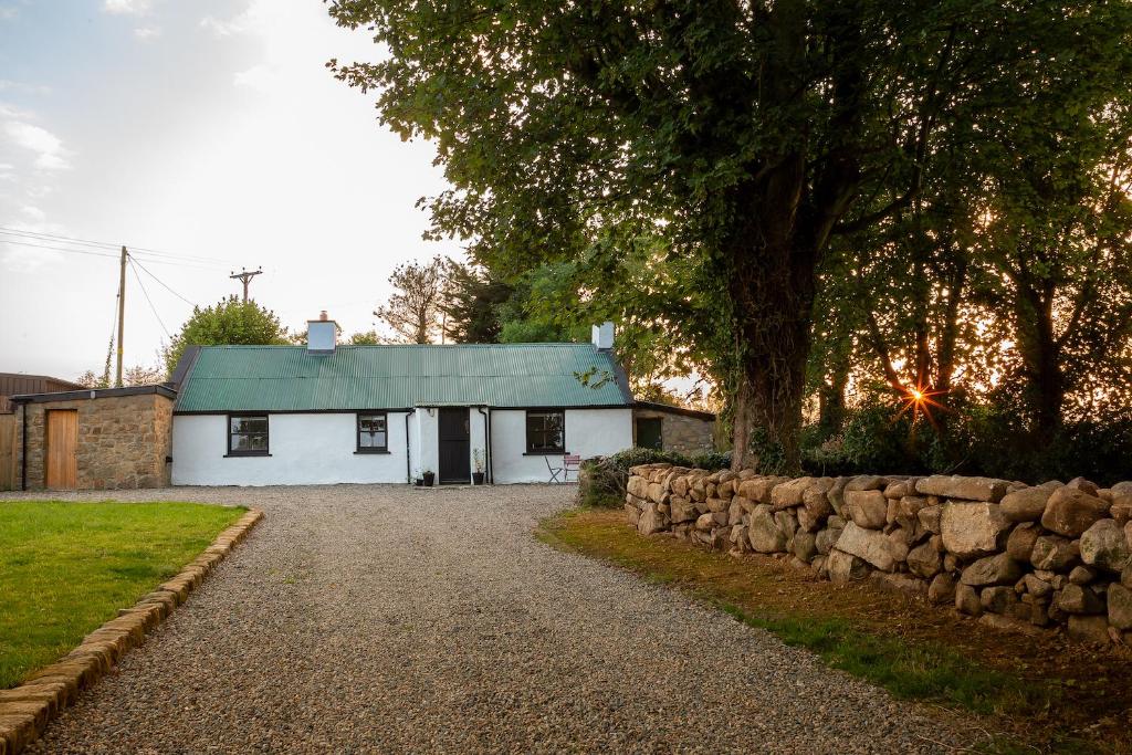 a white house with a green roof and a gravel driveway at Croan Cottage in Mayobridge