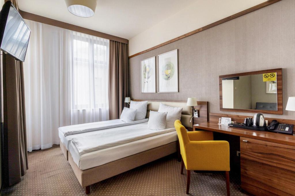 a hotel room with a large bed and a desk at Golden Tulip Krakow City Center in Kraków