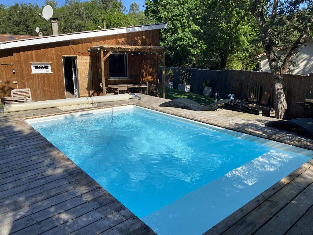einen großen blauen Pool auf einer Holzterrasse in der Unterkunft Maison à Biscarrosse: 8 pers, piscine, clim, proche lac et pistes cyclables, ménage inclus - FR-1-319-538 in Biscarrosse