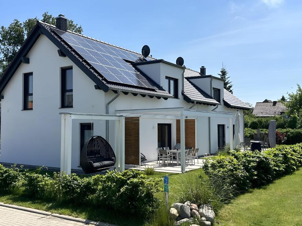 KrumminFerienhäuser Ankerplatz 1 und 2 Usedom mit Sauna, Kamin und Garten的屋顶装有太阳能电池板的白宫