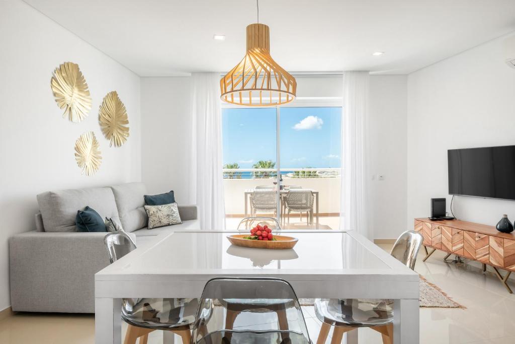 een woonkamer met een witte tafel en een bank bij Orange Beach Ocean View, Porto de Mós VR29 in Lagos