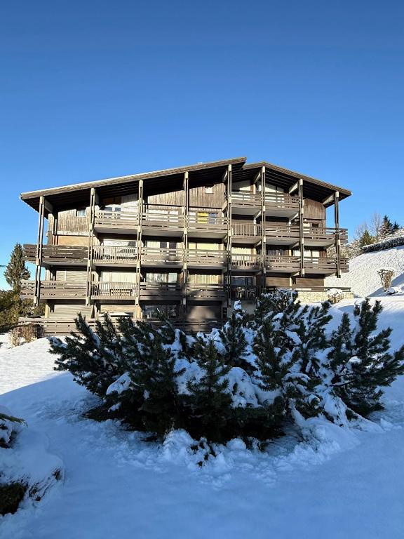 un bâtiment dans la neige avec des arbres devant dans l'établissement Résidence Le Floréal - Megève, à Megève