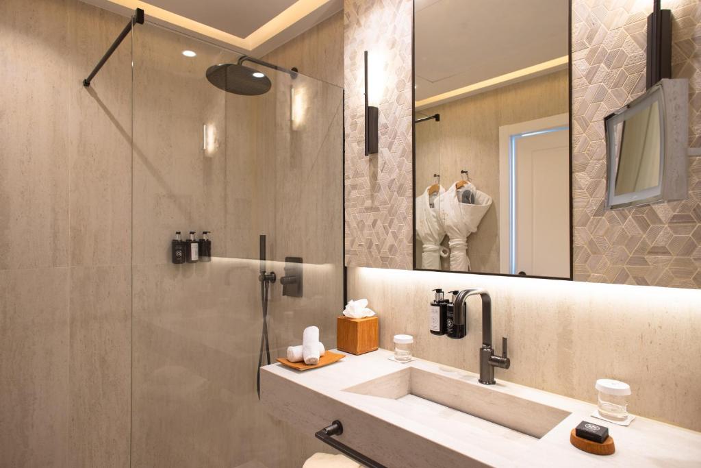 a bathroom with a sink and a shower with a mirror at Hotel Royal-Riviera in Saint-Jean-Cap-Ferrat