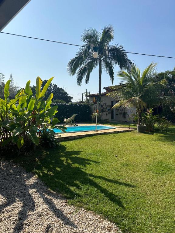 a yard with a swimming pool and palm trees at Sossego do Perequê in Ubatuba