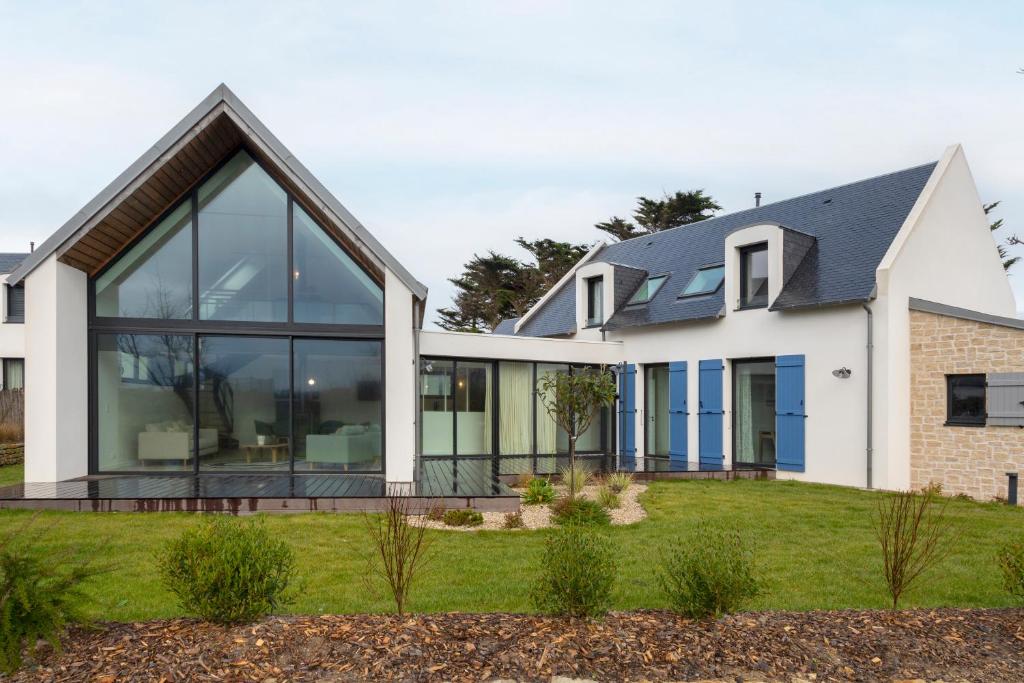 a house with large glass windows on a lawn at Villa Mer - 180m de la plage in Penmarcʼh
