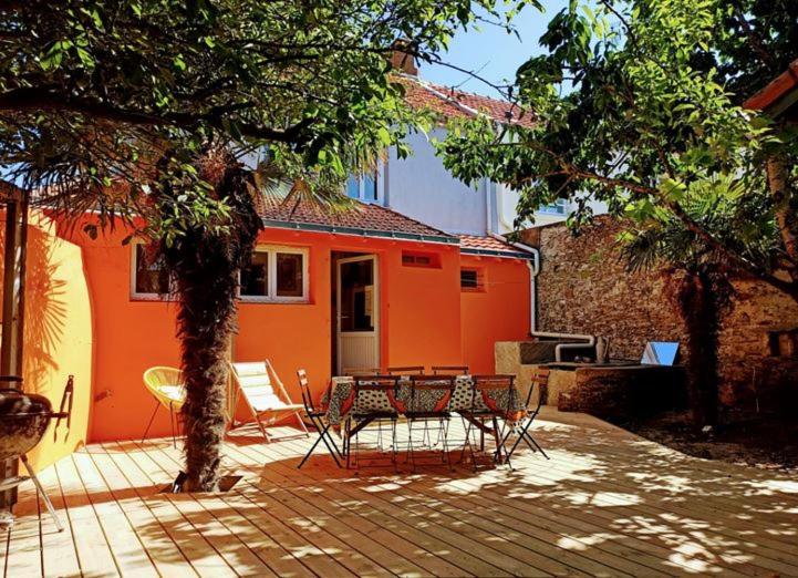 an orange house with a table and chairs on a patio at Maison de vacances - côte de Jade - coup de coeur in La Plaine-sur-Mer
