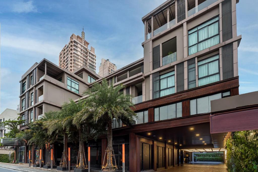 曼谷Metropolis Suites Bangkok, Tapestry Collection by Hilton的一座前面有棕榈树的建筑