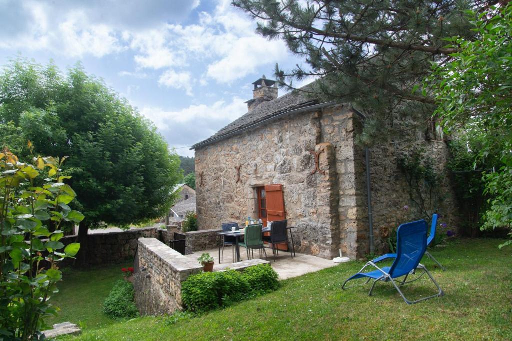 une maison en pierre avec une table et des chaises dans la cour dans l'établissement Aux cimes des gorges du tarn, à Laval-du-Tarn