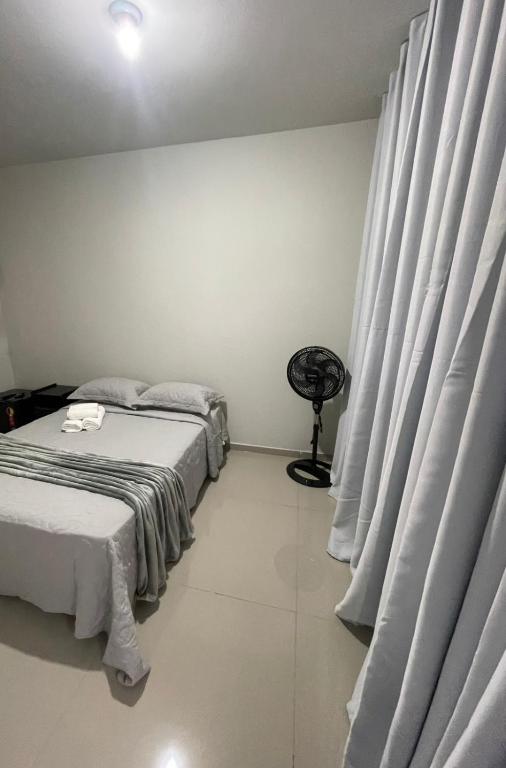 a bedroom with two beds with curtains and a fan at Caverna Suítes - Suítes na praça matriz in São Thomé das Letras