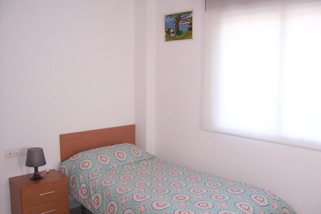 a small bedroom with a bed and a window at Pensión Nomphosumus in Cala del Moral