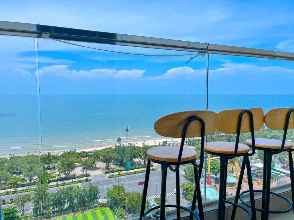 Una vista de la playa desde un bar con taburetes. en Mermaid seaview Vũng Tàu - Khang Apartment 1, en Vung Tau