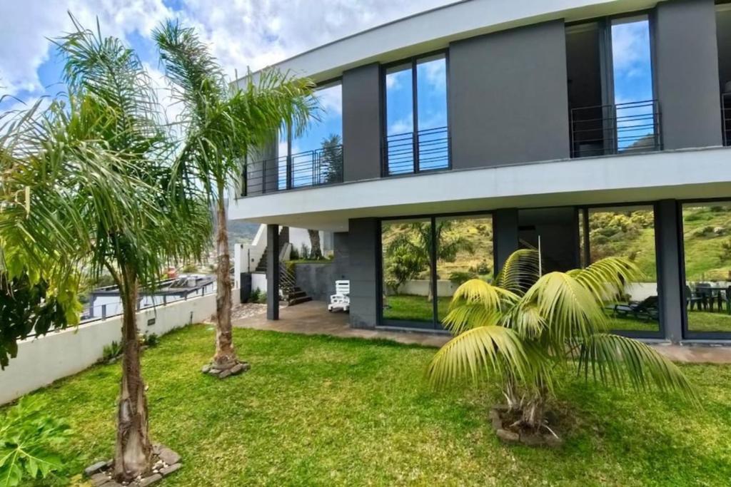 a house with palm trees in front of it at Sal e Pimenta House - A Wellbeing Retreat in Machico