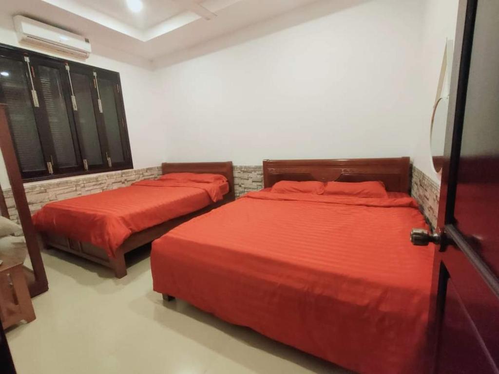 two beds in a room with red sheets at Villa Nhà Như in Phu Quoc