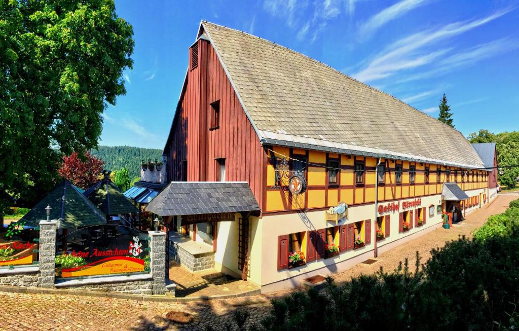 eine große rote Scheune mit einem Dach in der Unterkunft Naturhotel Gasthof Bärenfels in Kurort Altenberg
