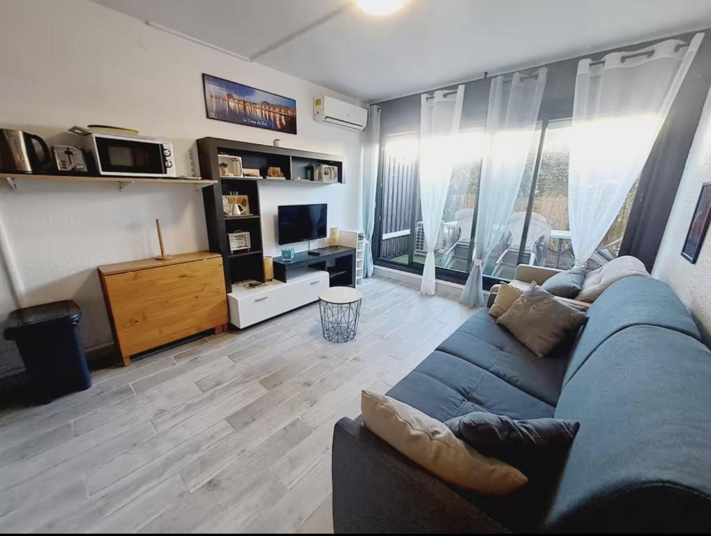 un salon avec un canapé bleu et une télévision dans l'établissement Joli studio à deux pas de la mer, au Grau-du-Roi