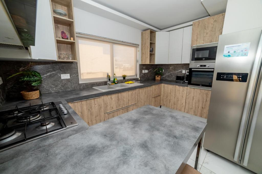 Una cocina con gabinetes de madera y electrodomésticos de acero inoxidable. en Peaceful Corner Penthouse 3 bed with views, en St Paul's Bay