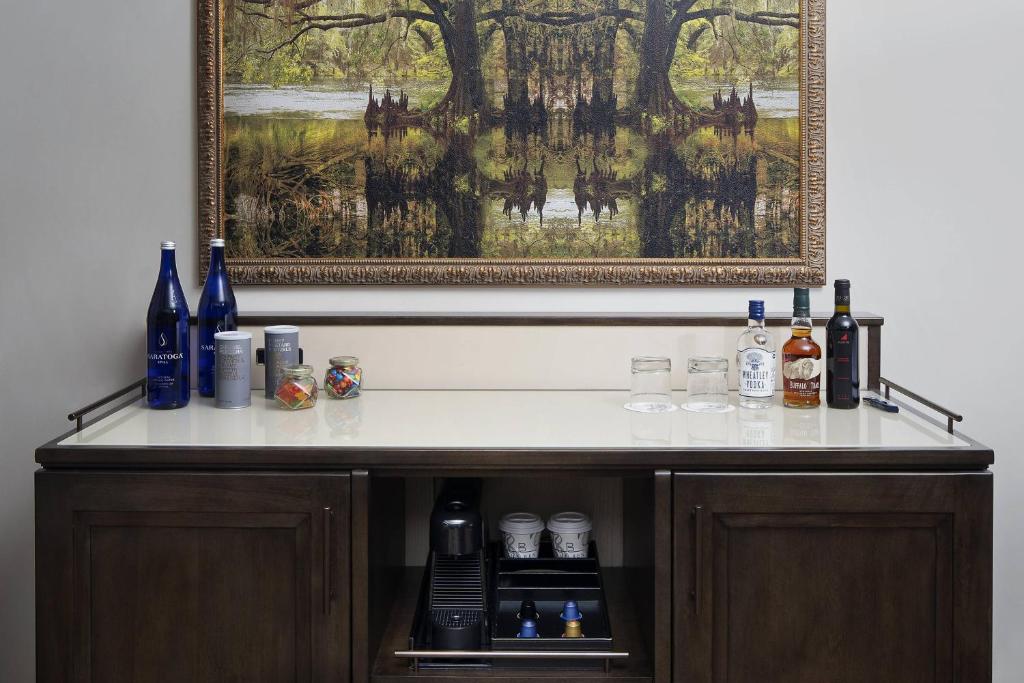 a bar with bottles and glasses and a painting at The Ben, Autograph Collection in West Palm Beach