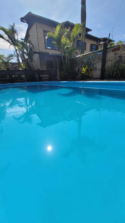 a large blue swimming pool in front of a house at Pousada Uluwatu, Praia do Rosa in Praia do Rosa