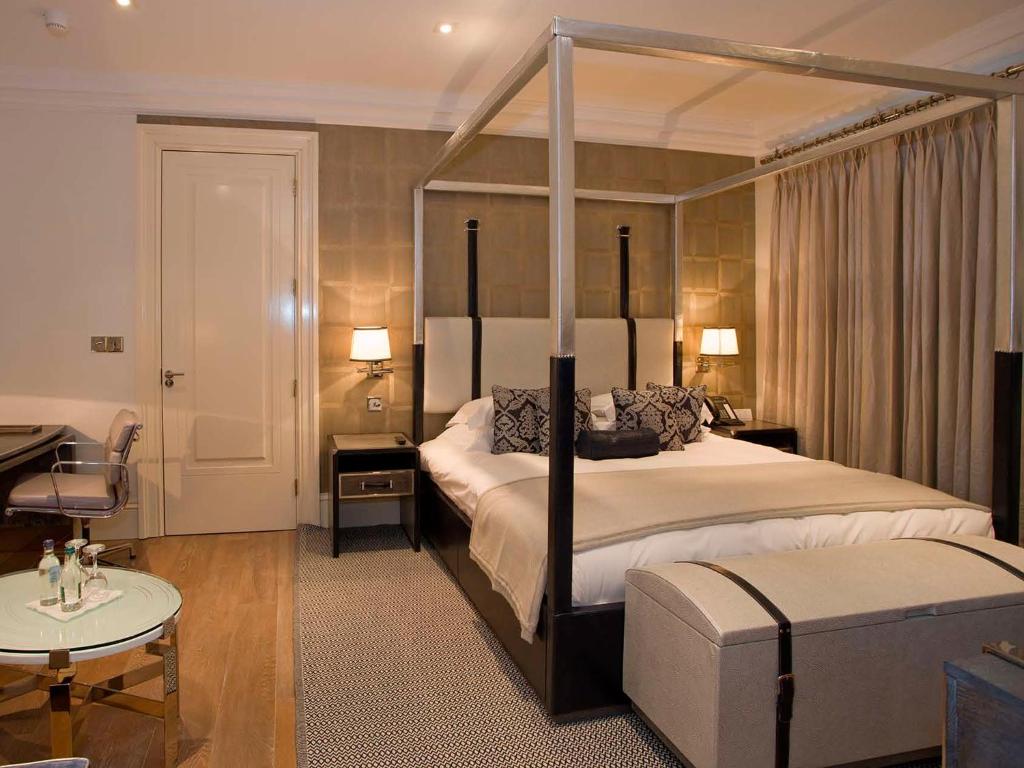 Langtons Hotel Kilkenny في كيلكيني: غرفة نوم مع سرير المظلة وطاولة