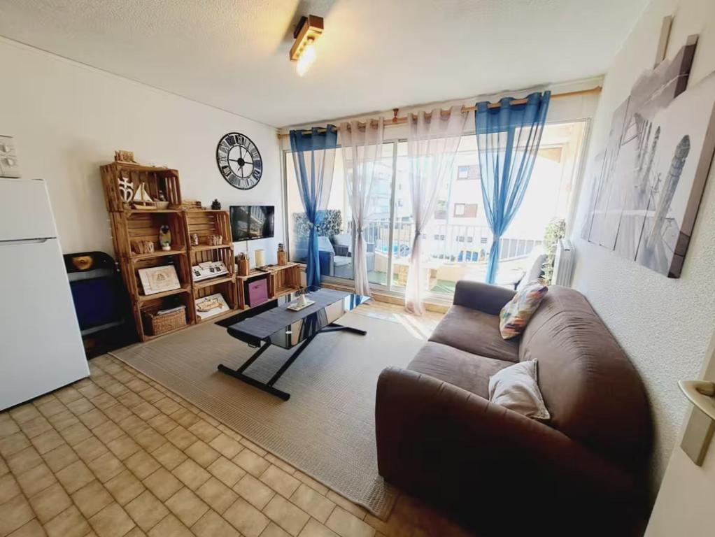 - un salon avec un canapé, une table et un réveil dans l'établissement Le confort près de la plage, au Grau-du-Roi