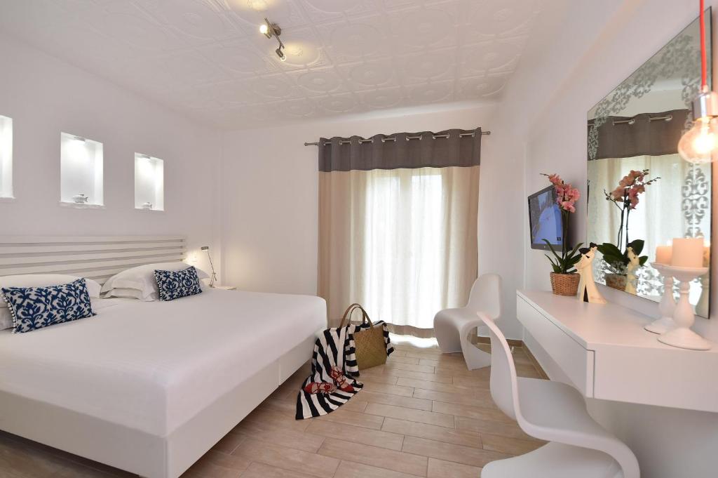a white bedroom with a white bed and a desk at Apollon Boutique Hotel in Parikia