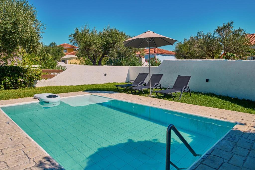 ein Swimmingpool mit zwei Stühlen und einem Sonnenschirm in der Unterkunft Villa Nefeli Periyali in Vasilikos