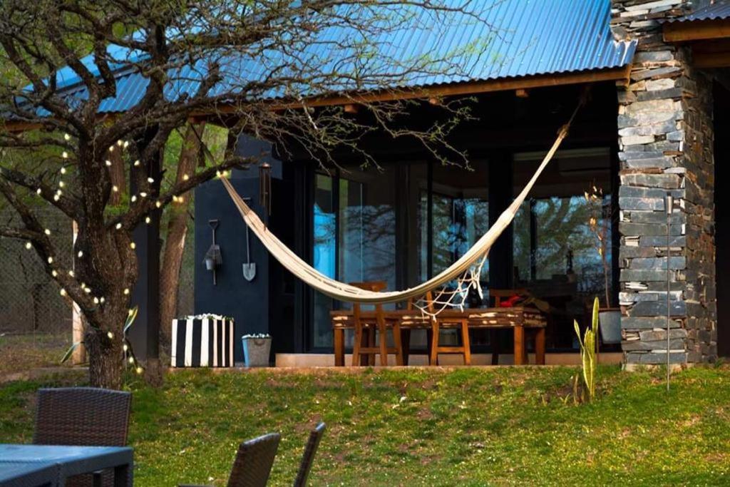 a hammock hanging from a tree in front of a house at LunaNegra Casas de descanso in Villa General Belgrano