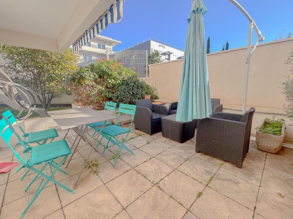 un patio avec une table, des chaises et un parasol dans l'établissement Central avec jardin, piscine parking 150 m plage, Fréjus, à Fréjus