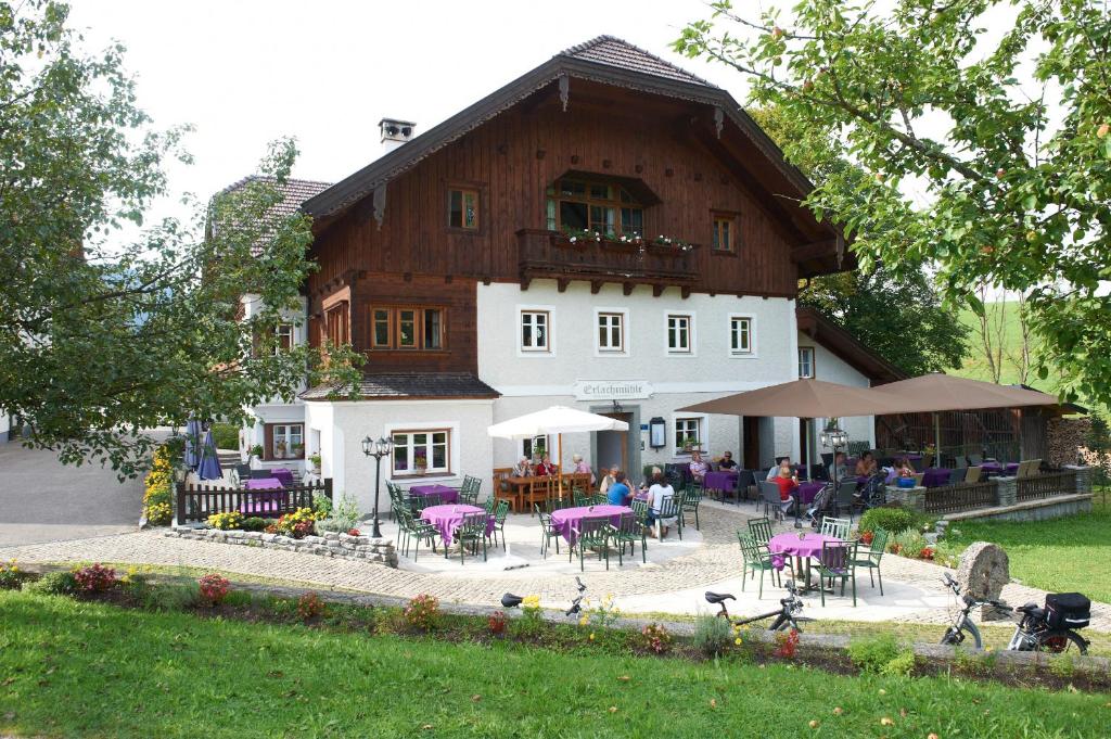 un gran edificio con mesas y sillas delante de él en Erlachmühle, en Mondsee