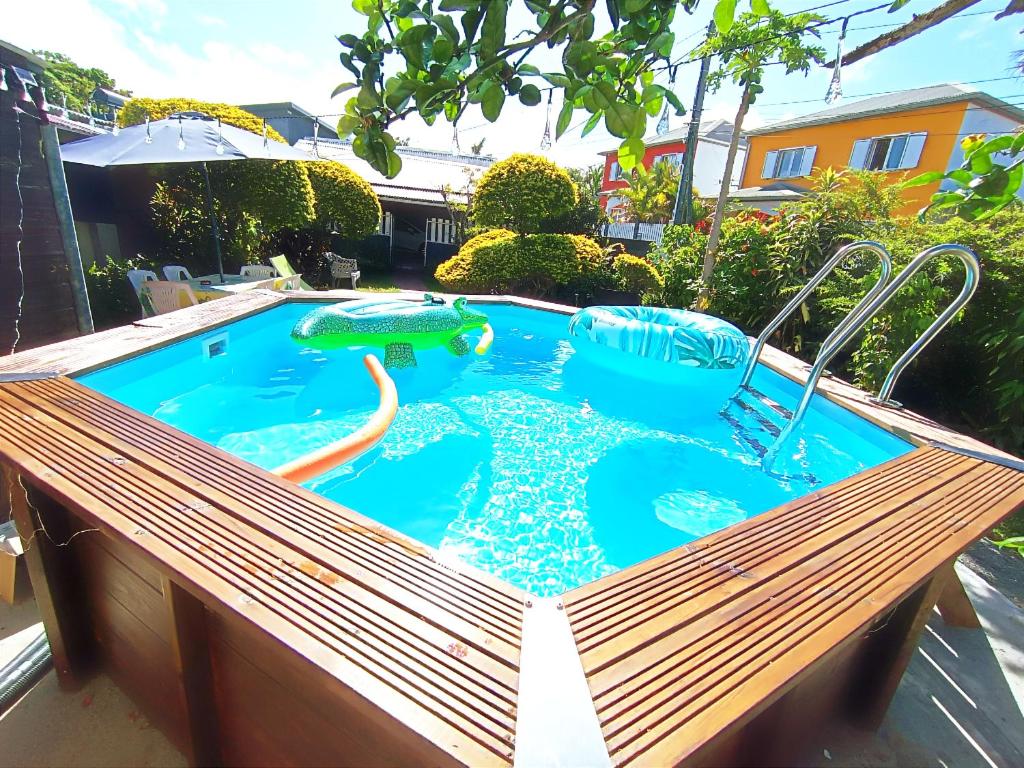 a swimming pool with a wooden bench in a backyard at Chambre privée 2 - Case créole Le Mistral,chez Kévin in Saint-André