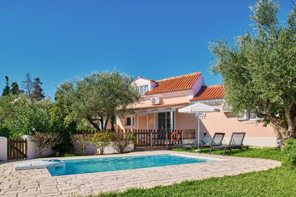 a villa with a swimming pool in front of a house at Villa Cleo Periyali in Vasilikos
