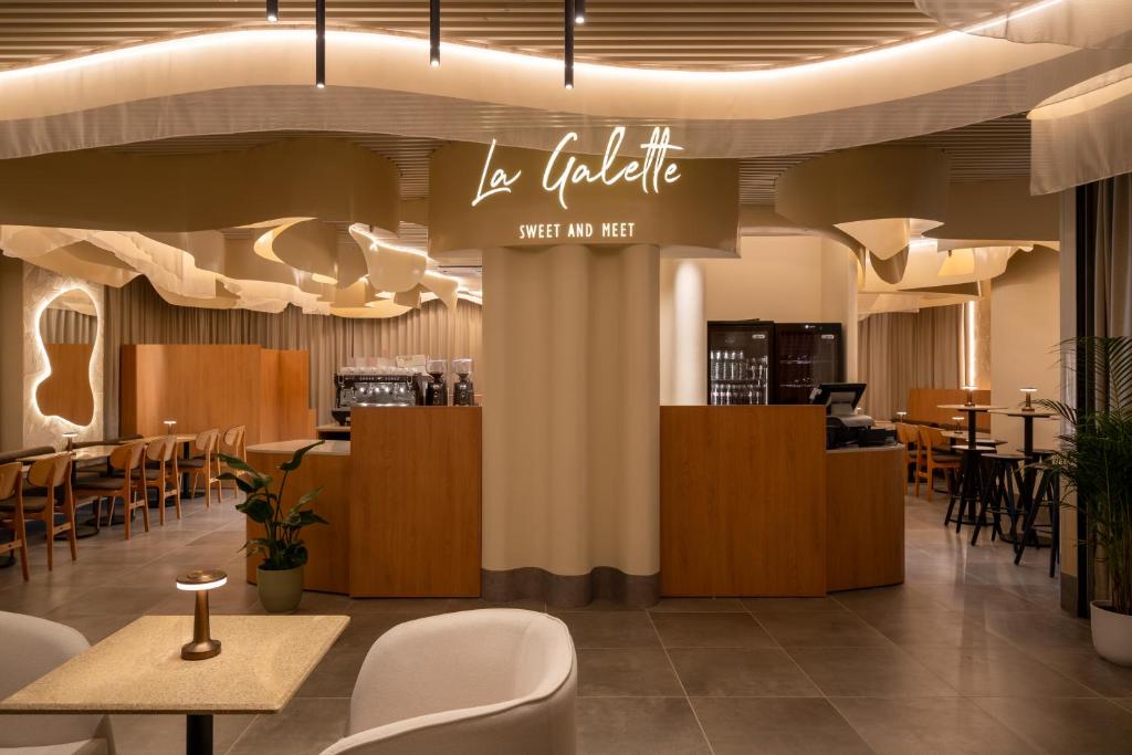 a restaurant with tables and chairs and a sign at Pullman Bucharest World Trade Center in Bucharest