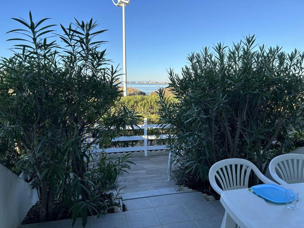 un patio avec une table et des chaises et l'océan dans l'établissement Port Camargue, T2 climatisé, terrasse, parking, animaux admis - FR-1-250-219, au Grau-du-Roi