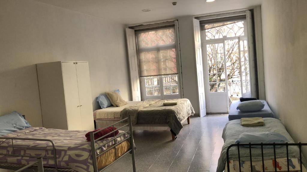 una habitación con tres camas y una ventana en Casa Augusta 3, en Braga