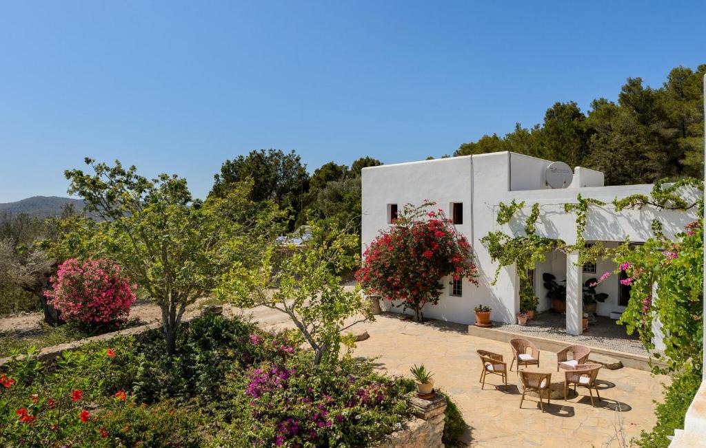 un edificio blanco con mesas, sillas y flores en Villa Can Felix, en Santa Gertrudis