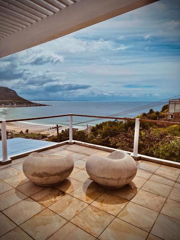 a balcony with two chairs and a view of the ocean at Watching Waves, Heron Chase in Fish Hoek