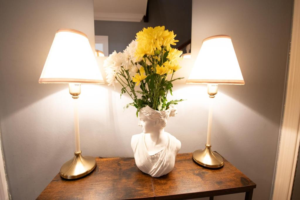 a vase of flowers on a table with two lamps at Harrods Flats in London
