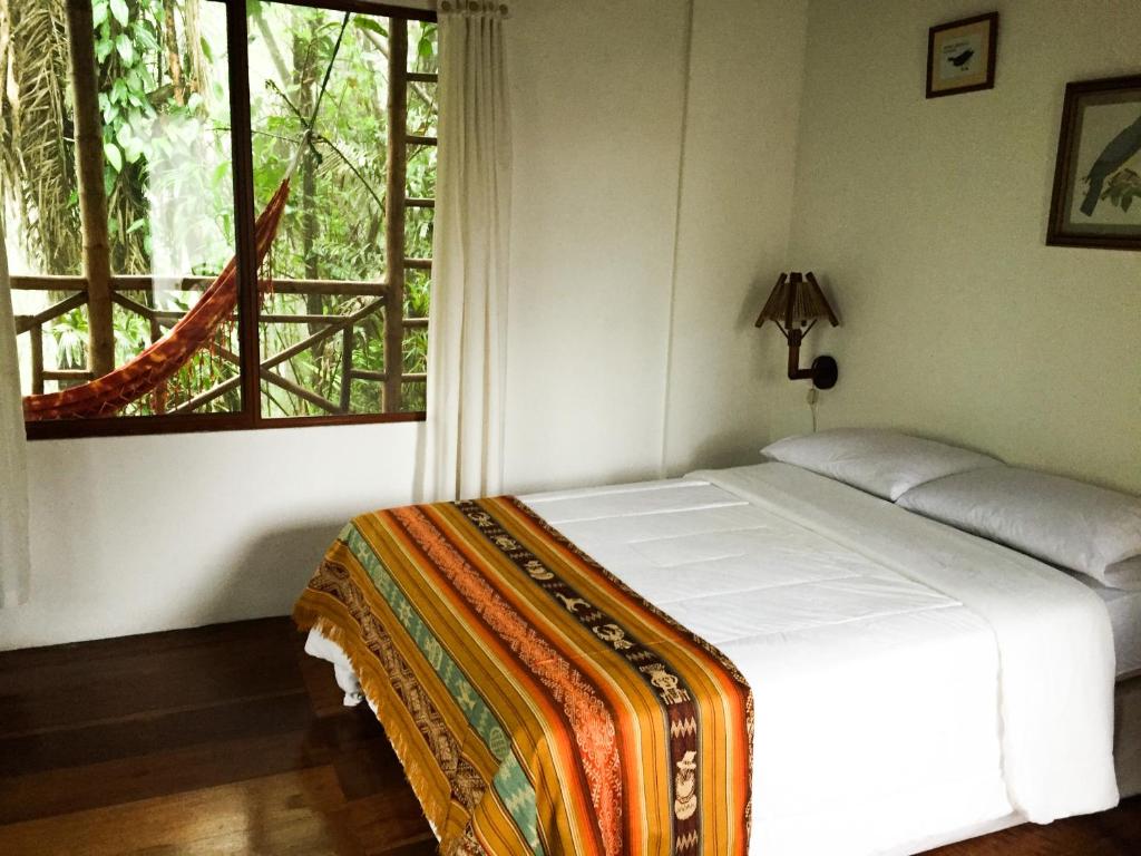 Bett in einem Zimmer mit einem großen Fenster in der Unterkunft Pacoche Lodge in Pacoche
